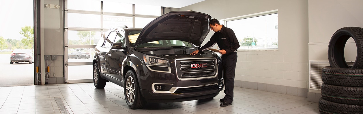 tech checking a GMC's engine